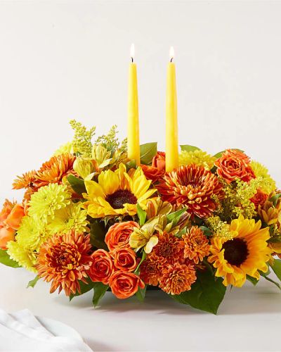 <p data-start="120" data-end="551">Celebrate the warmth and wonder of fall with the Autumn Harmony Centerpiece—a rich and radiant floral arrangement designed to bring people together. Whether you’re hosting a harvest feast, sending thanks to someone special, or simply adorning your own table, this centerpiece adds the perfect seasonal touch. Glowing with the colors of autumn and accented by candlelight, it turns any gathering into a cozy and elegant celebration.</p>
<p data-start="553" data-end="1053">This deluxe arrangement showcases a vibrant mix of fall’s favorite blooms—golden sunflowers, burnt orange roses, crimson mums, and deep red carnations—all nestled in a bed of fresh autumn greens and accents. At its heart are glowing taper candles, ready to add warmth and ambiance to any dinner table or holiday display. Rustic touches like fall leaves, berries, and sprigs of eucalyptus bring texture and charm, while the low, full design ensures a perfect fit for family tables and festive spreads.</p>
<p data-start="1055" data-end="1465">The Autumn Harmony Centerpiece is ideal for Thanksgiving, Friendsgiving, seasonal dinner parties, or simply surprising someone with a beautiful expression of gratitude. The palette captures the changing leaves, crackling fires, and cozy evenings of the season, making it just as meaningful as it is beautiful. It’s a gift that brings the whole room together—perfect for hosts, family, or anyone who loves fall.</p>
<p data-start="1467" data-end="1868">Every centerpiece is thoughtfully arranged and hand-delivered by a local florist to ensure the freshest flowers and the finest presentation. Rosa’s La Hacienda is proud to offer local delivery throughout the Boca Raton area, making it easy to send the beauty of the season directly to someone’s home or office. With our commitment to care and quality, each bouquet arrives ready to impress and uplift.</p>
<p data-start="1870" data-end="2012" data-is-last-node="" data-is-only-node="">Add warmth, color, and candlelight to your fall traditions with the Autumn Harmony Centerpiece—a seasonal favorite that speaks from the heart.</p>